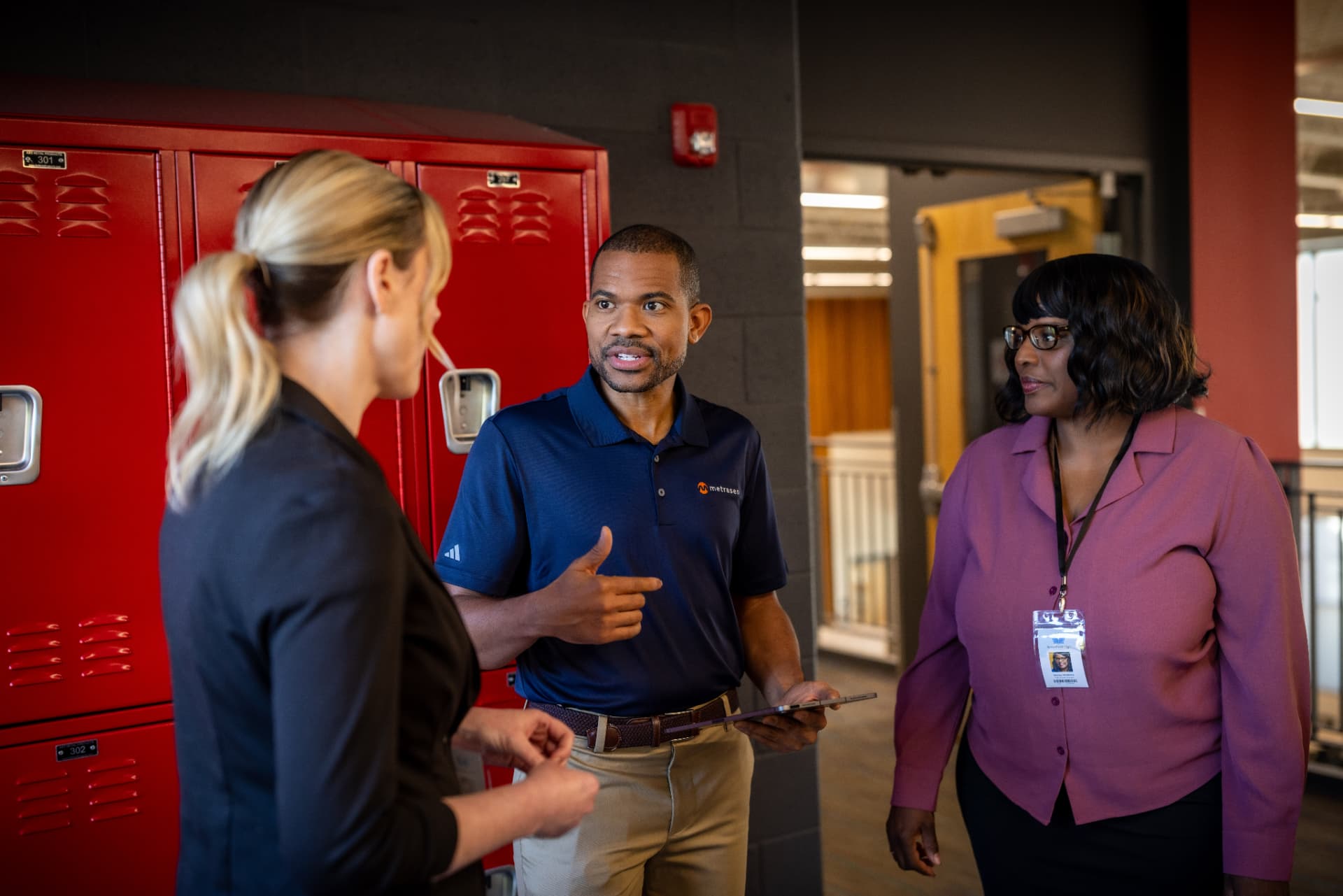 A Metrasens specialist talking with two school administrators in a hallway.