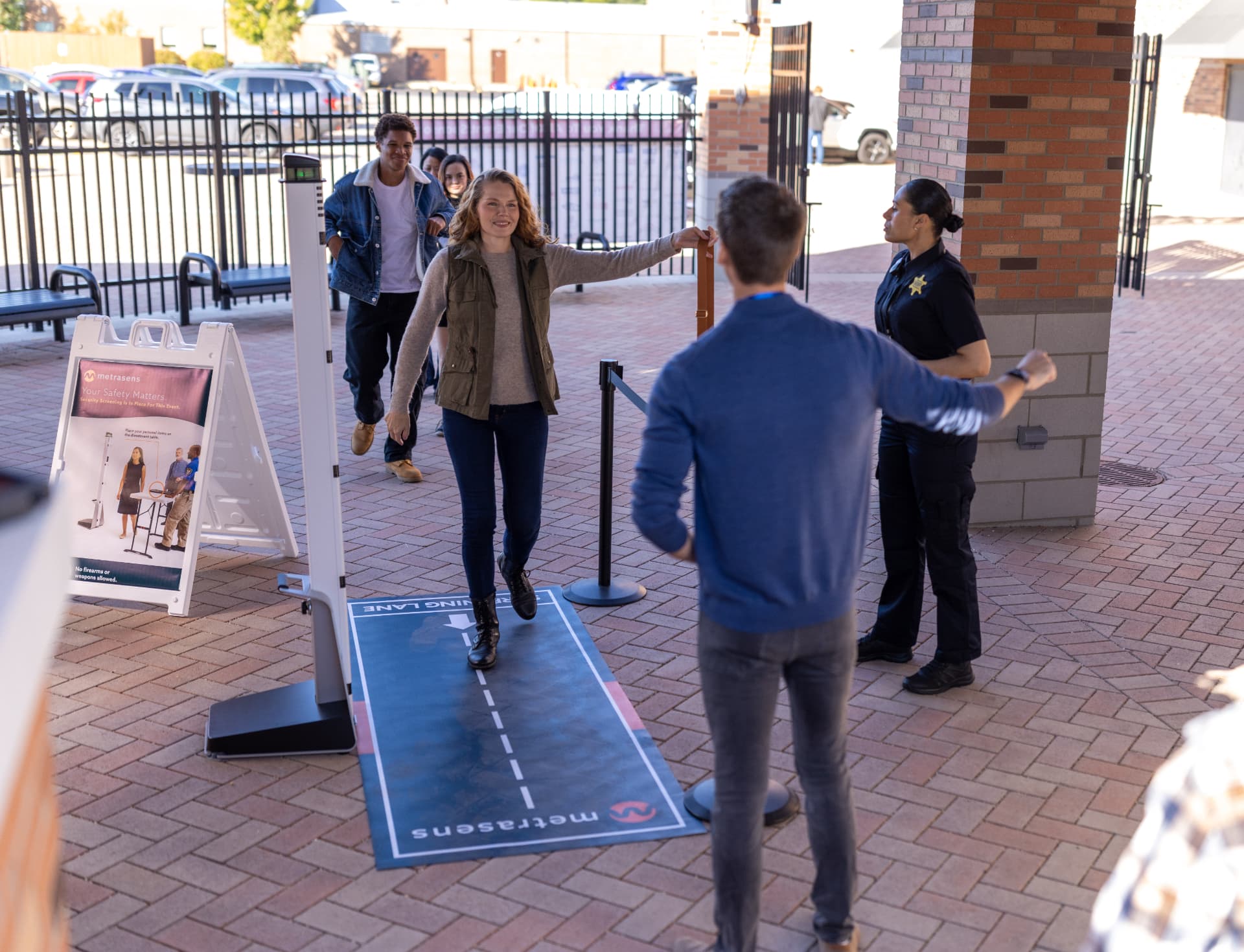 Visitors walking through a Metrasens Ultra screening lane at a school event entrance.
